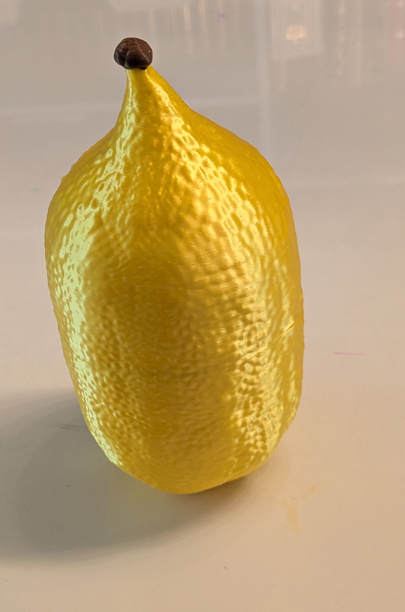 A 3D-printed esrog case, closed, resembling a real citron with its stem intact.